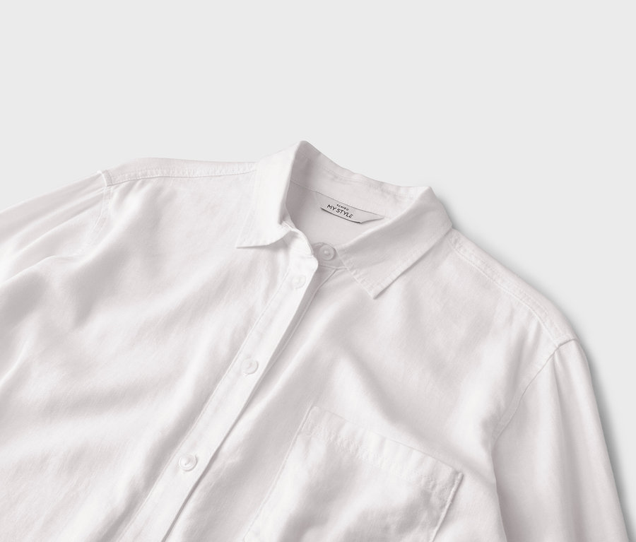 Gros plan d'une chemise blanche boutonnée avec une poche.