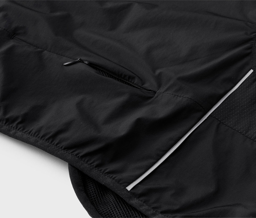 Gros plan d'un gilet noir avec une poche zippée et des détails réfléchissants.