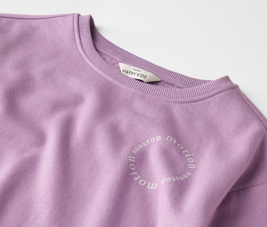 Gros plan sur un sweat-shirt violet avec l'inscription "nonstop motion".