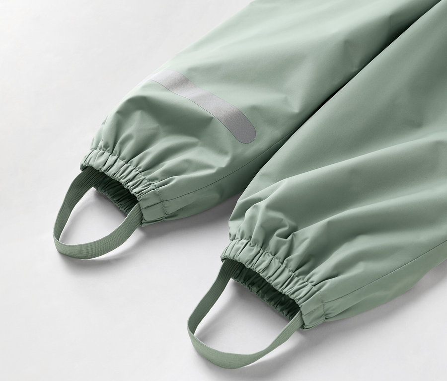 Gros plan sur le bas d'un pantalon vert clair avec des poignets élastiques et des boucles de pied.