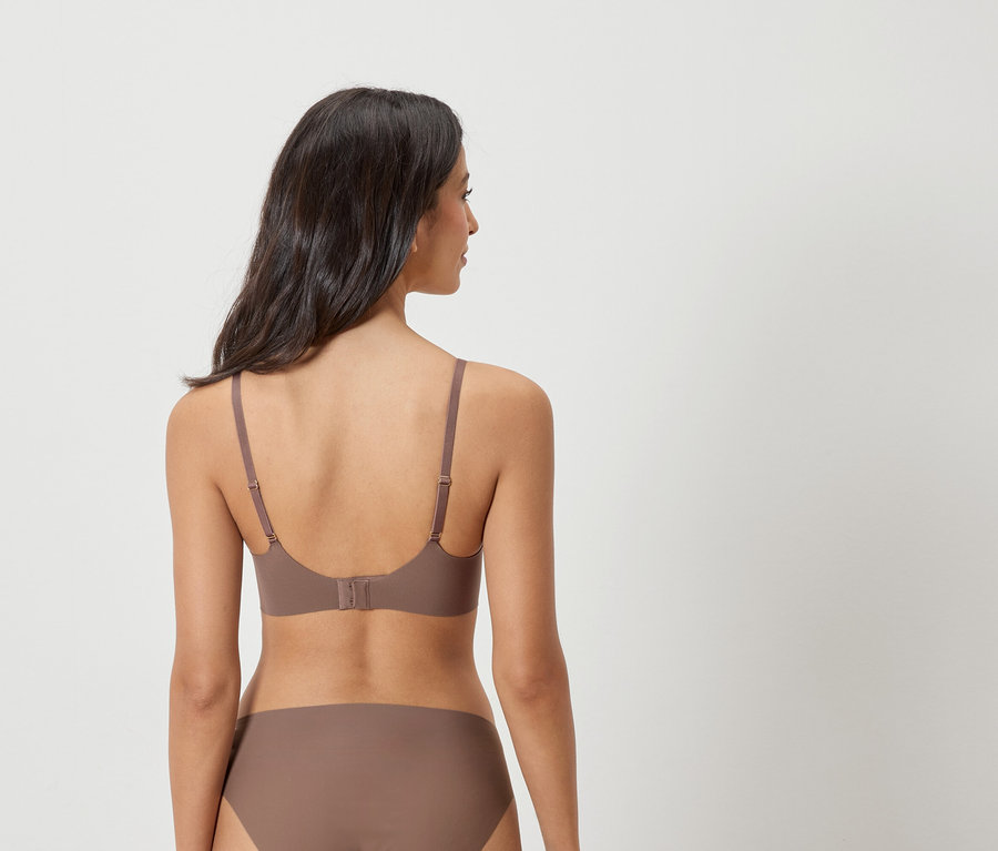Vue arrière d'une femme aux cheveux foncés portant un soutien-gorge et une culotte marron.