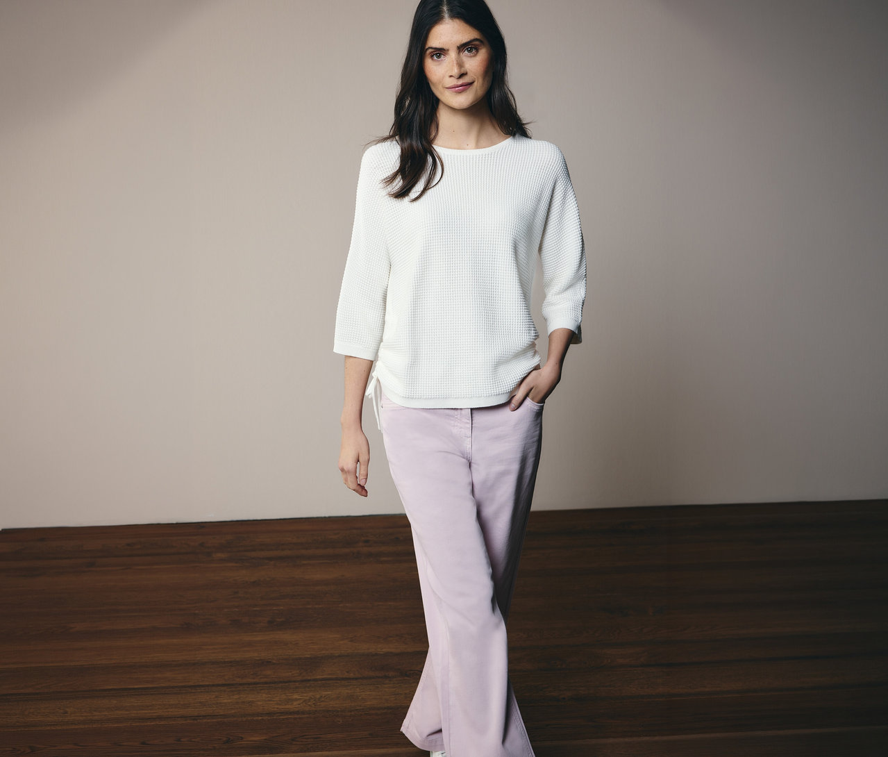 Une femme pose, portant un pull en maille fine CECIL et un jean CECIL « Neele ».