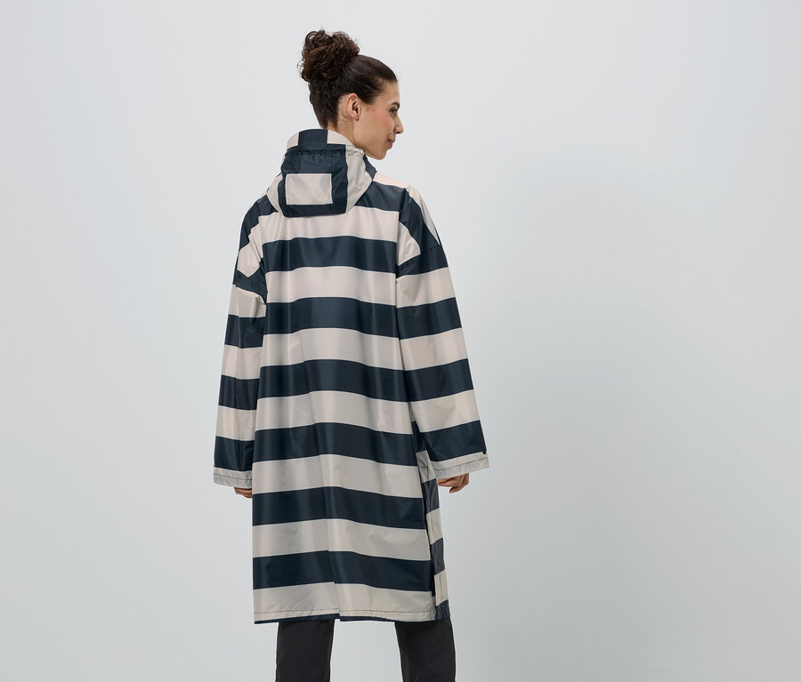 Une femme portant un chignon est vêtue d'un imperméable rayé bleu marine et beige, vue de dos.