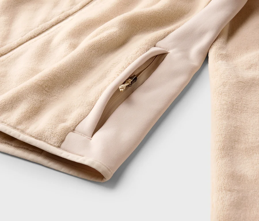 Gros plan d'une veste en polaire beige avec fermeture éclair et poche zippée.