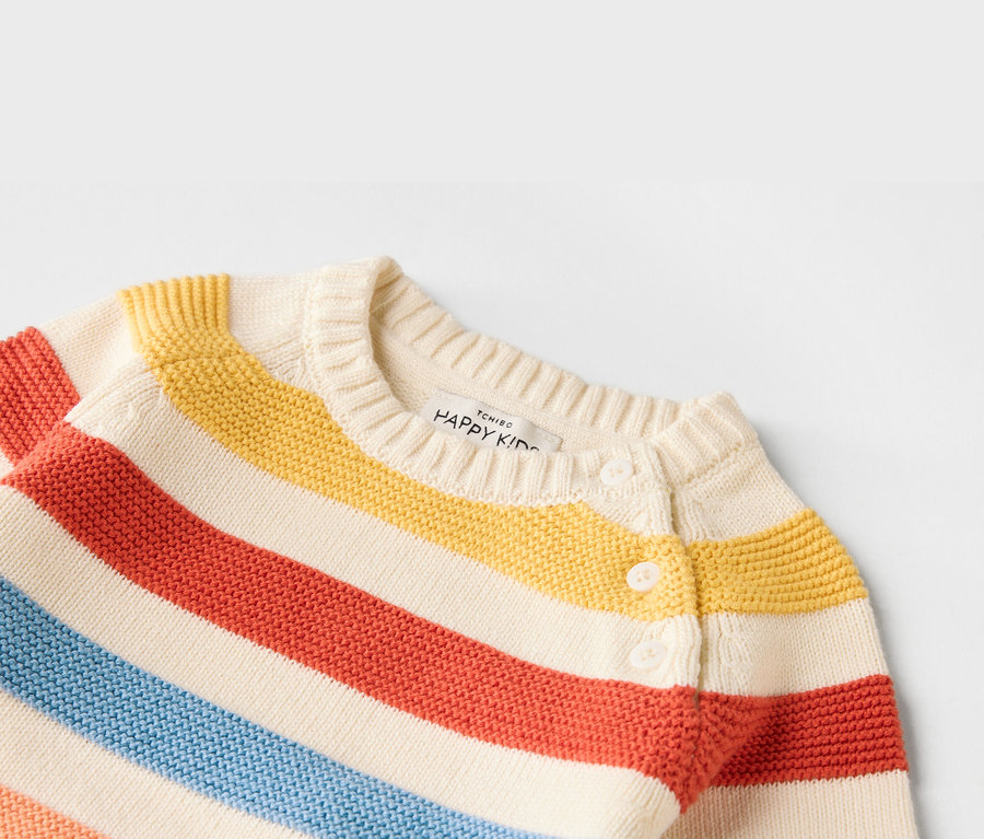 Gros plan d'un cardigan rayé pour enfant dans les tons rouge, jaune et bleu avec des boutons blancs.