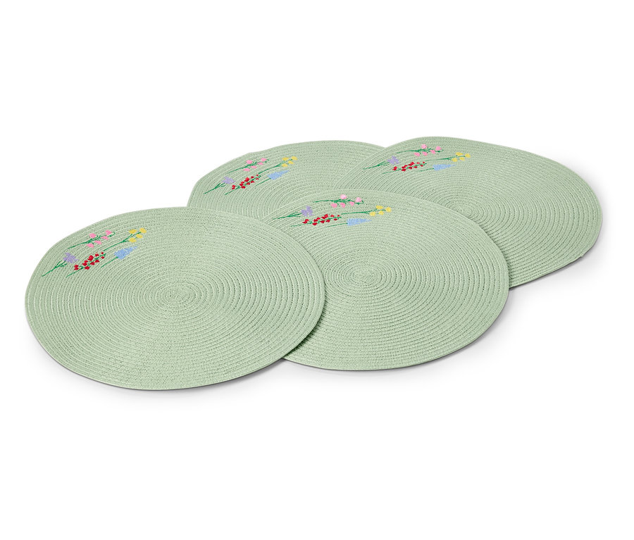 Quatre sets de table ronds vert clair avec des motifs floraux brodés sont posés les uns sur les autres.