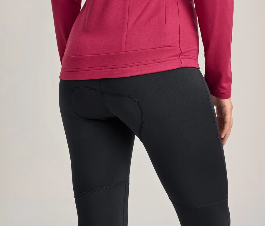Personne de dos portant un haut magenta à manches longues et un cuissard de cyclisme noir avec insert rembourré.