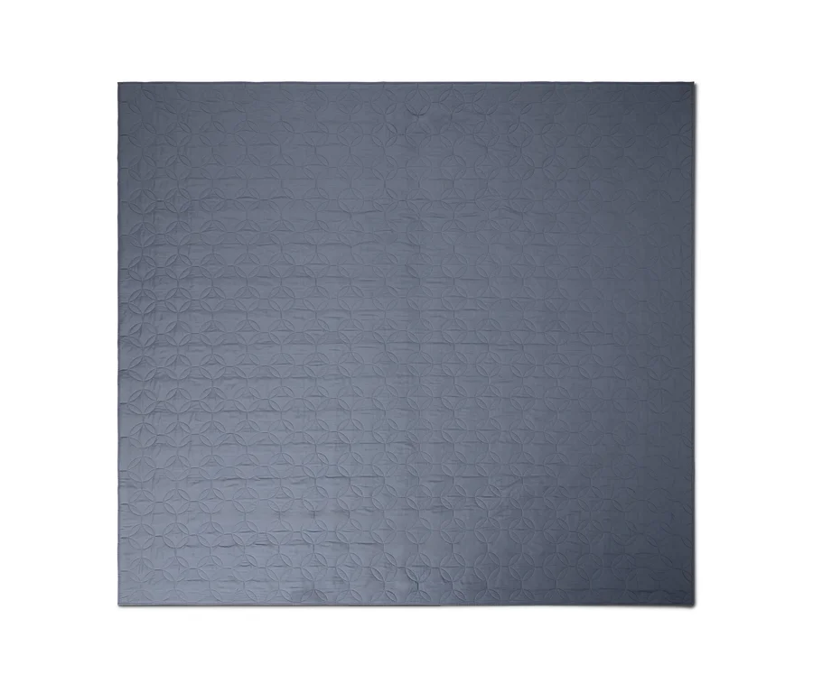 Couverture matelassée bleu-gris avec un motif géométrique de cercles entrelacés.