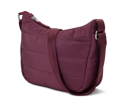 Un sac à main matelassé bordeaux avec une bandoulière réglable posé sur un fond blanc.