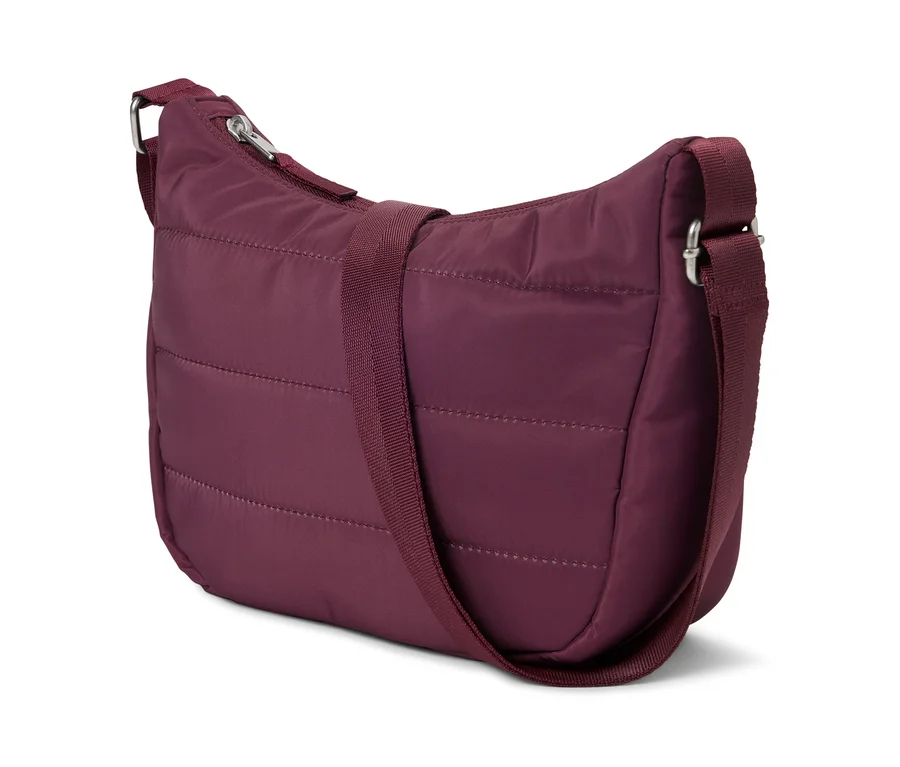 Un sac à main matelassé bordeaux avec une bandoulière réglable posé sur un fond blanc.