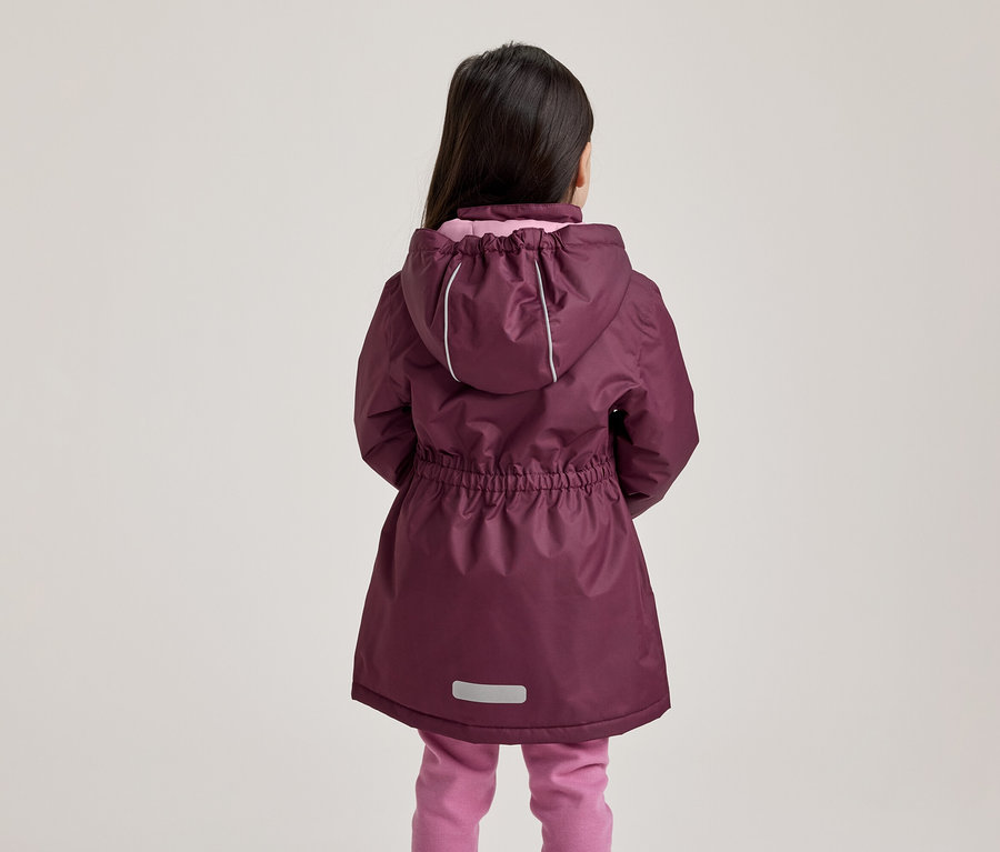 Enfant de dos portant une veste prune à capuche avec des bandes réfléchissantes et un pantalon rose.