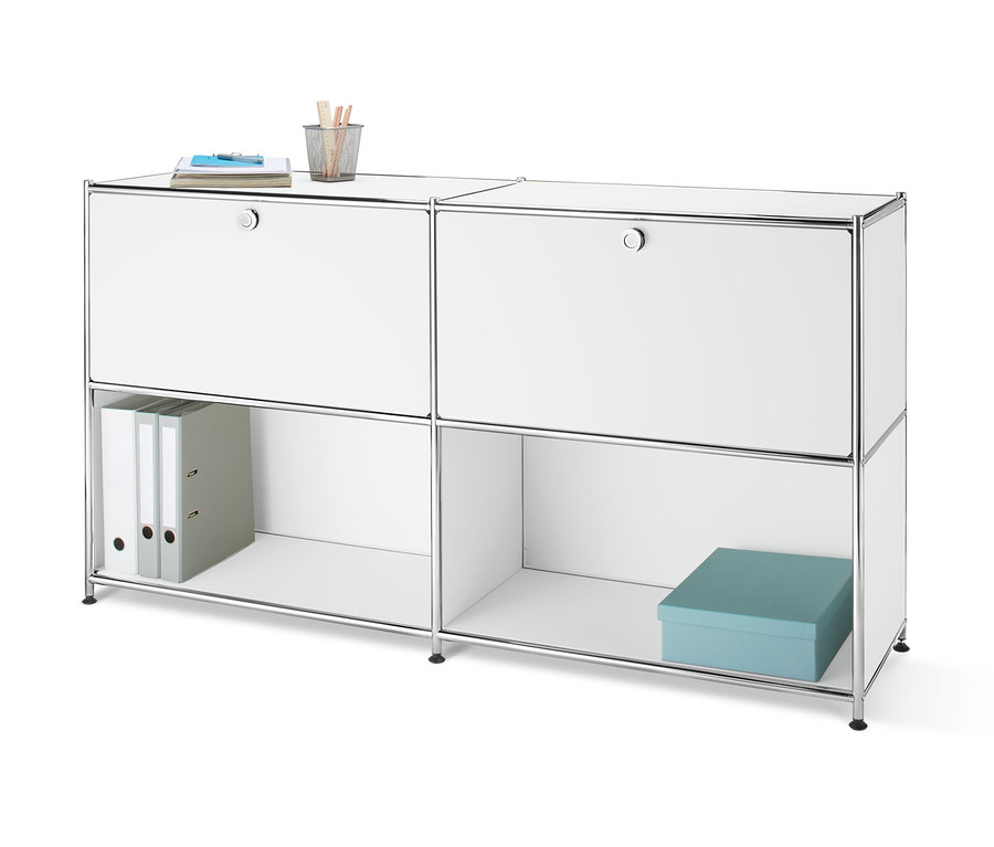 Vue de face d'un buffet en métal avec 2 compartiments à abattants amovibles sur lequel reposent un carnet et un pot à crayons. Deux classeurs et une boîte bleue se trouvent dans un compartiment ouvert.