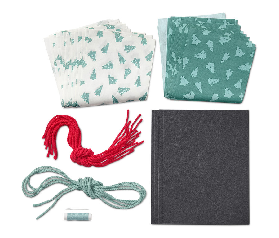 Kit de couture « Calendrier de l’Avent en tissu » avec des tissus blancs et verts, de la ficelle rouge et bleue et des cartes noires.