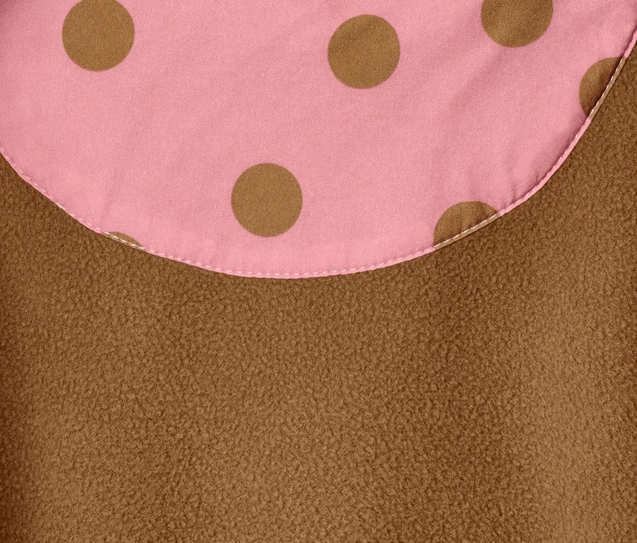 Détail d'une combinaison softshell avec des pois marron sur un fond rose et une texture polaire marron.