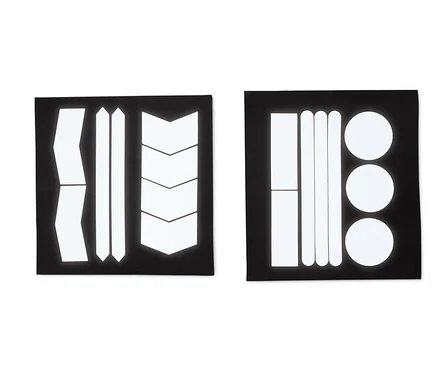 Deux feuilles noires avec des autocollants réfléchissants de différentes formes : bandes, flèches et cercles.