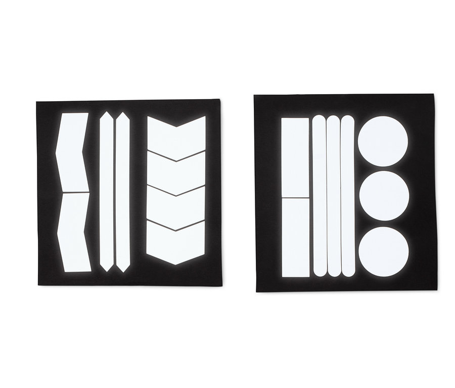 Deux feuilles noires avec des autocollants réfléchissants de différentes formes : bandes, flèches et cercles.