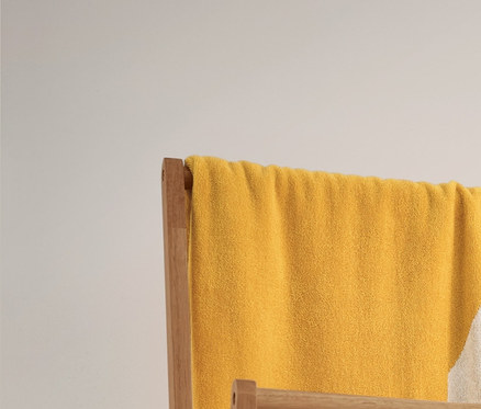 Un très grand linge de bain en jacquard jaune et blanc à rayures et 2 linges de toilette beige et blanc à rayures sont suspendus à un portant à vêtements pliable. En dessous se trouvent 2 paniers de rangement.