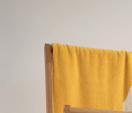 Un très grand linge de bain en jacquard jaune et blanc à rayures et 2 linges de toilette beige et blanc à rayures sont suspendus à un portant à vêtements pliable. En dessous se trouvent 2 paniers de rangement.