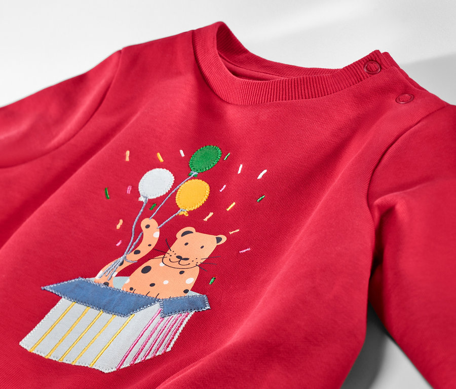 Sweat-shirt enfant rouge avec intérieur gratté et patch d'un animal avec des ballons sortant d'une boîte.