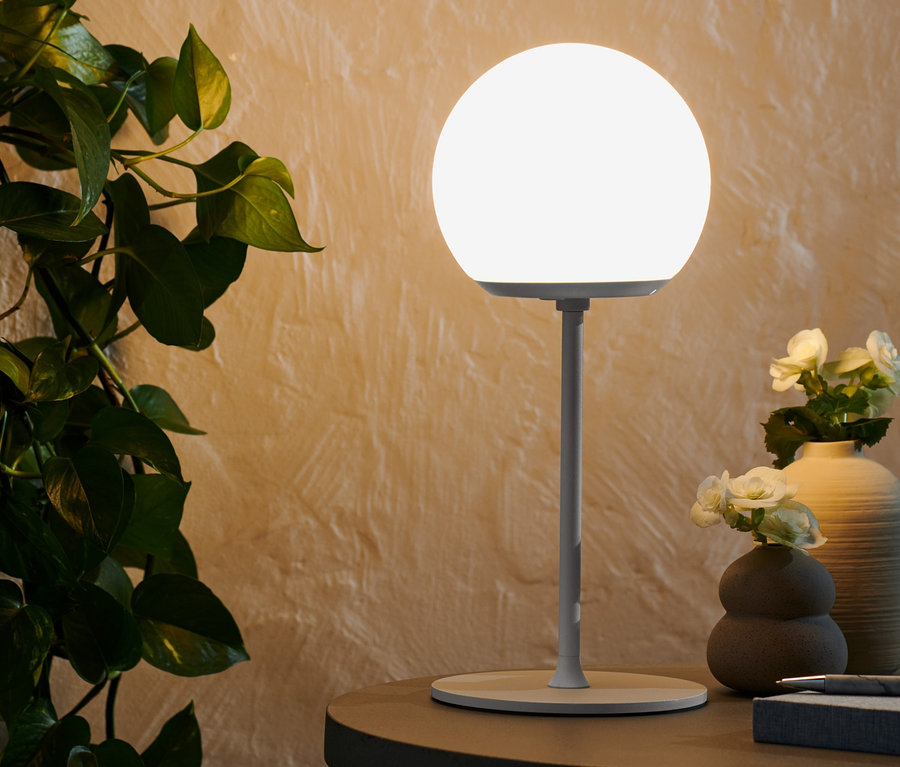 Une lampe de table à LED sans fil allumée est posée sur une table.