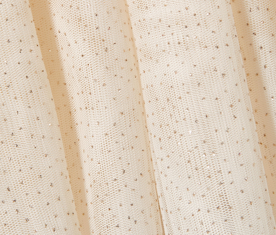 Gros plan d'une jupe en tulle couleur crème pour tout-petits avec de délicats points dorés.