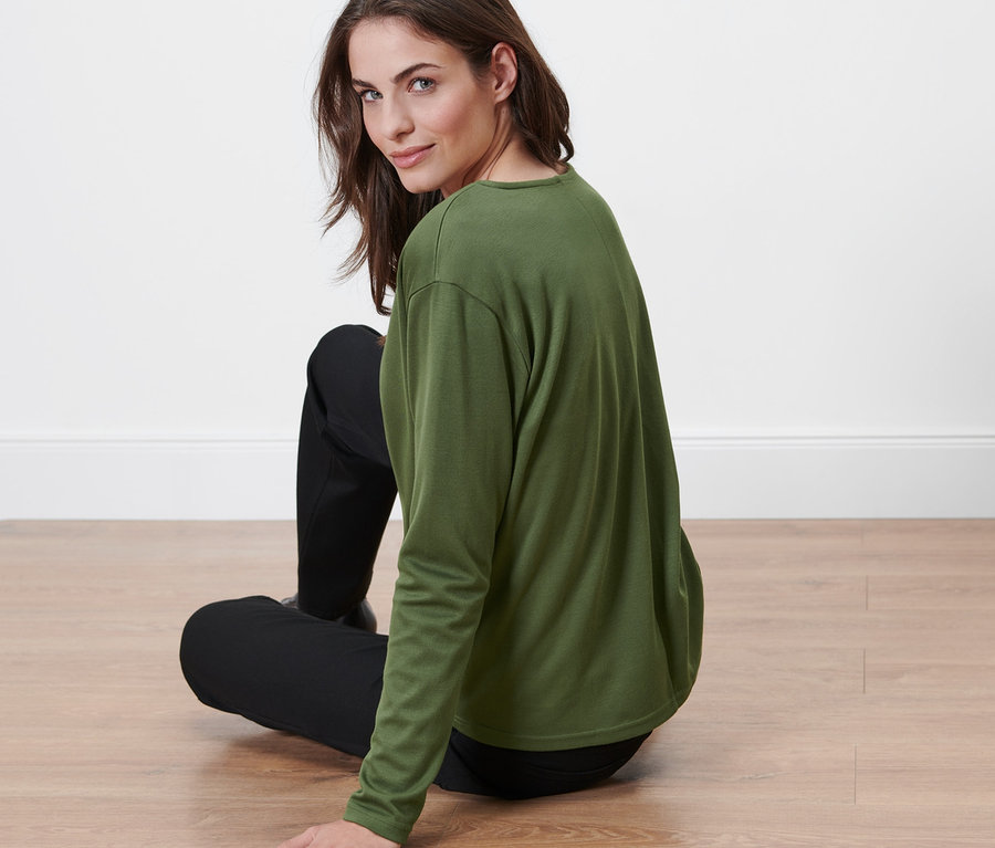 Femme assise par terre portant une blouse.
