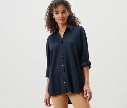 Femme posant dans un chemisier en jersey piqué bleu foncé et un pantalon marron.