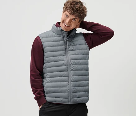 Un homme pose en gilet matelassé à ranger gris.