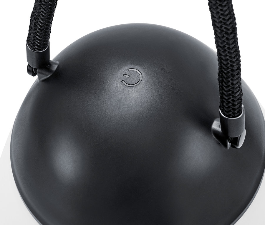 Gros plan d'une lampe à LED rechargeable avec batterie interchangeable supplémentaire, avec un dessus noir et un cordon.