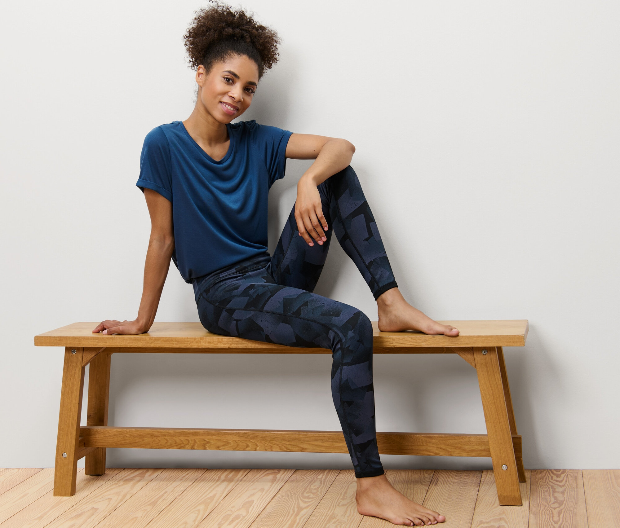 Femme assise sur un banc portant un legging de sport réversible, noir/bleu marine.