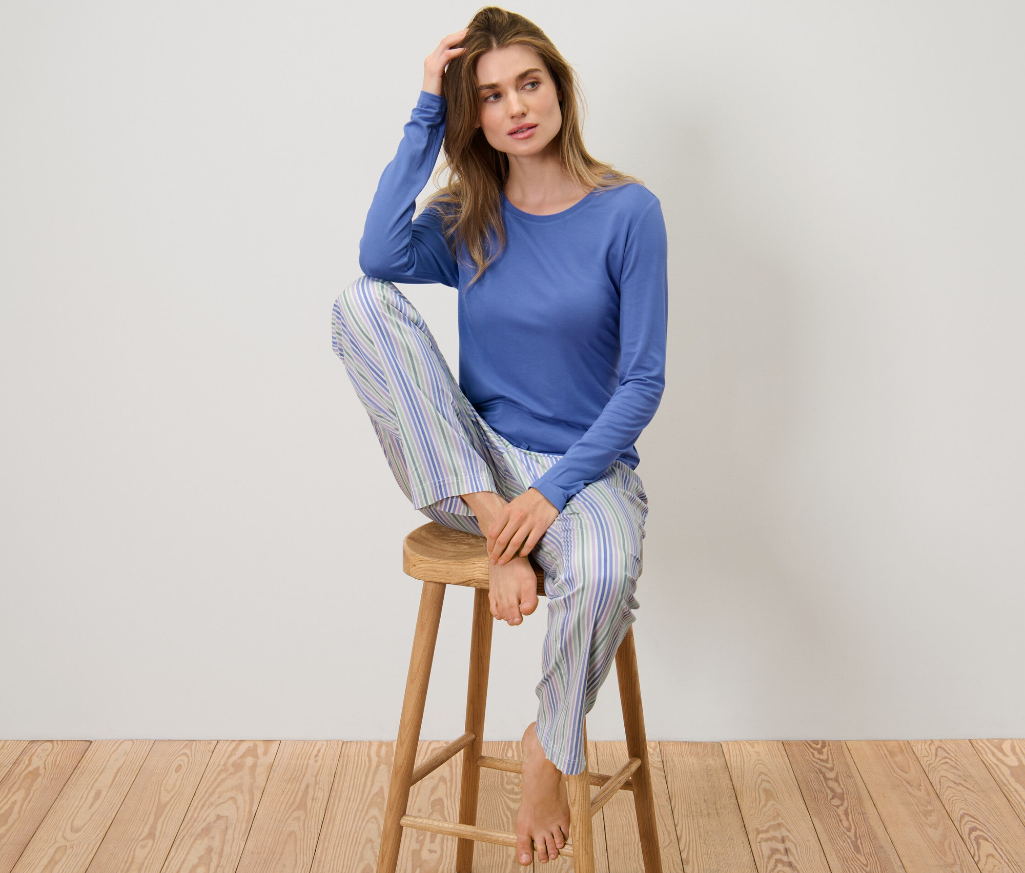 Femme assise sur un tabouret en pyjama avec un pantalon tissé.