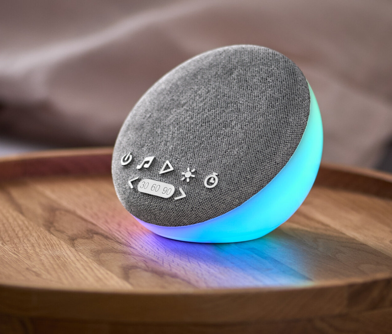 Un appareil d’aide au sommeil avec haut-parleur et sonorités naturelles est posé sur une table de chevet.