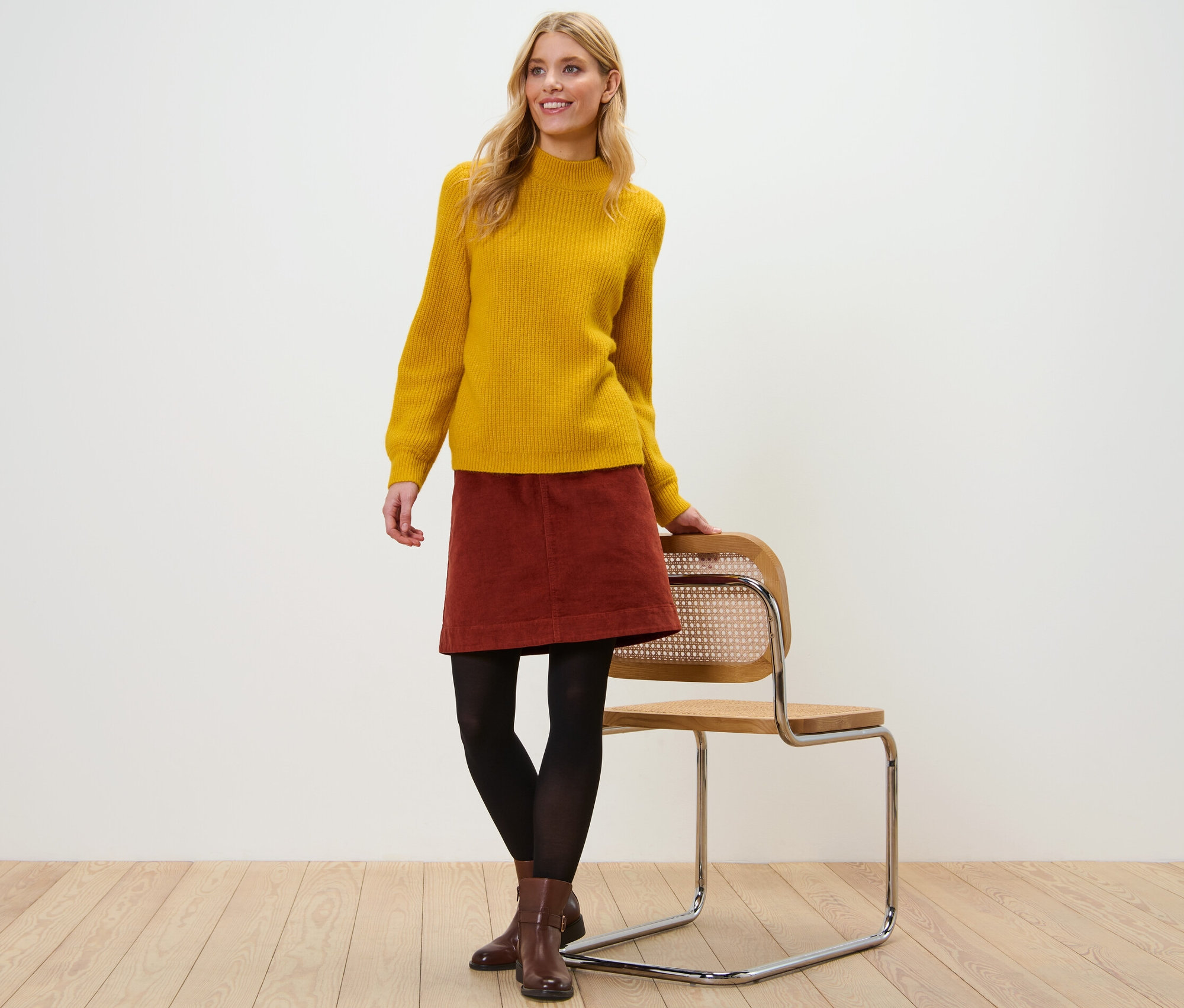 Femme posant en pull jaune et jupe en velours.