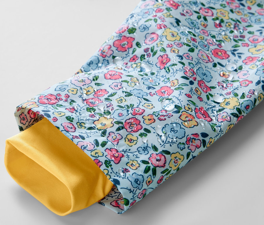 Gros plan sur une veste de pluie pour enfant à motif floral avec une doublure de manche jaune.
