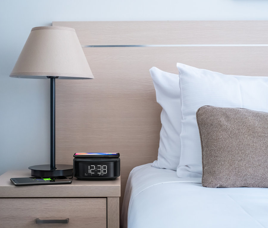 Table de chevet avec lampe et radio-réveil DAB Philips « TAR7705 », sur lequel repose un smartphone.
