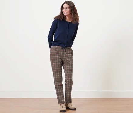 Une femme debout portant un cardigan bleu marine et un jogpant à motif pied-de-poule.
