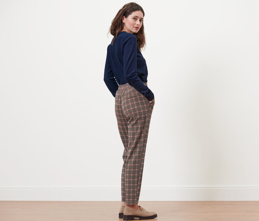 Femme posant en jogpant à motif pied-de-poule et pull bleu.