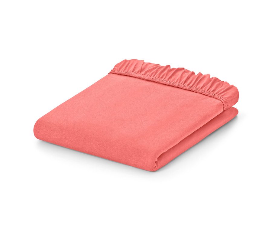 Draps-housses en jersey couleur papaye pliés de différentes tailles sur fond blanc.