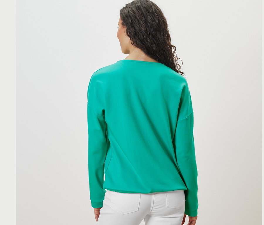 Vue arrière d'une femme aux cheveux foncés portant un sweat-shirt turquoise.
