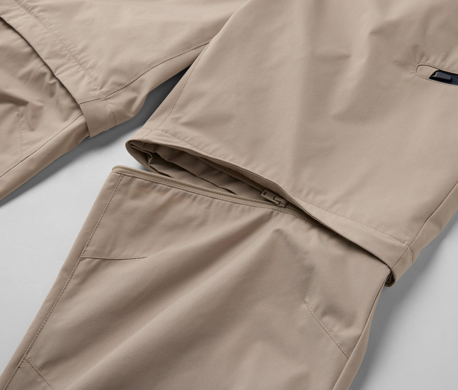 Détail d'un pantalon technique 2 en 1 beige avec une fermeture éclair.