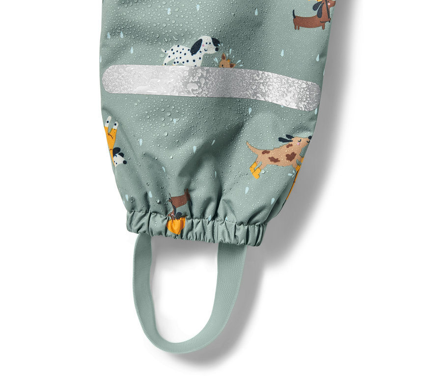 Détail d'un pantalon de pluie thermique pour enfant avec un imprimé de chiens, une bande réfléchissante et des gouttes d'eau.