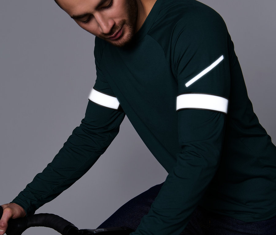Homme en haut à manches longues vert tenant un guidon de vélo. Il porte 2 Bandes réfléchissantes pour pantalons.