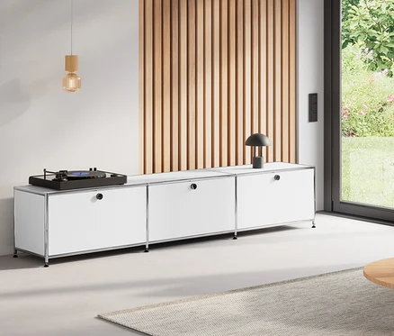 Salon avec table basse ronde de 80	cm, meuble bas en métal «	CN3	» à 3	abattants blanc, jeu d'abattants supplémentaires en métal « CN3 », orange, et suspension en bois.
