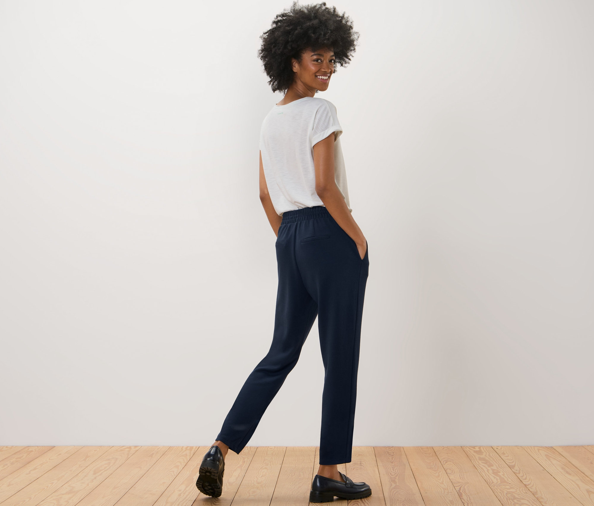 Femme posant en pantalon de jogging bleu marine et t-shirt blanc.