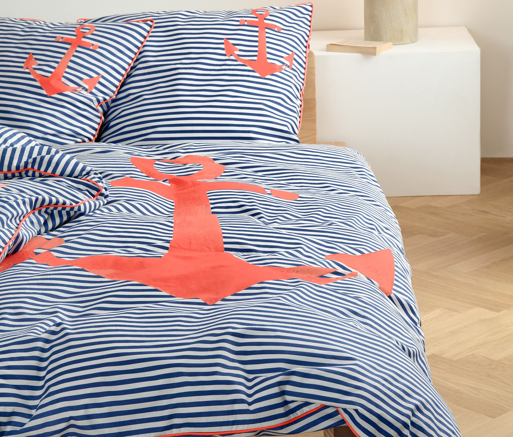 Parure de lit en percale rayée avec motif d'ancre sur un lit.