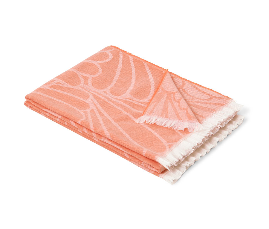 Couverture de salon réversible avec franges et motif floral orange pliée.