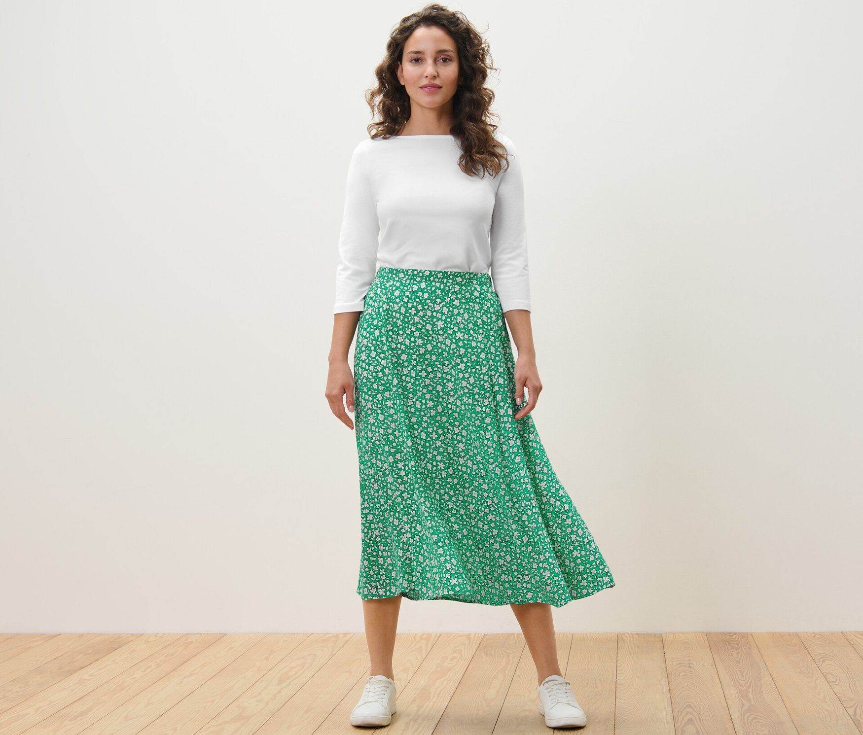 Femme debout portant une jupe midi imprimée, verte.