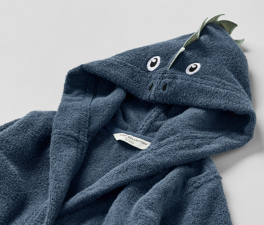 Gros plan sur un peignoir bleu pour enfant avec une capuche à motif de dragon.