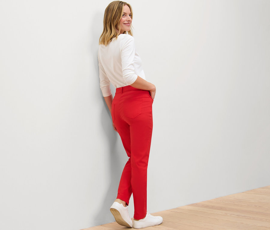 Une femme regarde par-dessus son épaule et pose en pantalon en bengaline rouge.