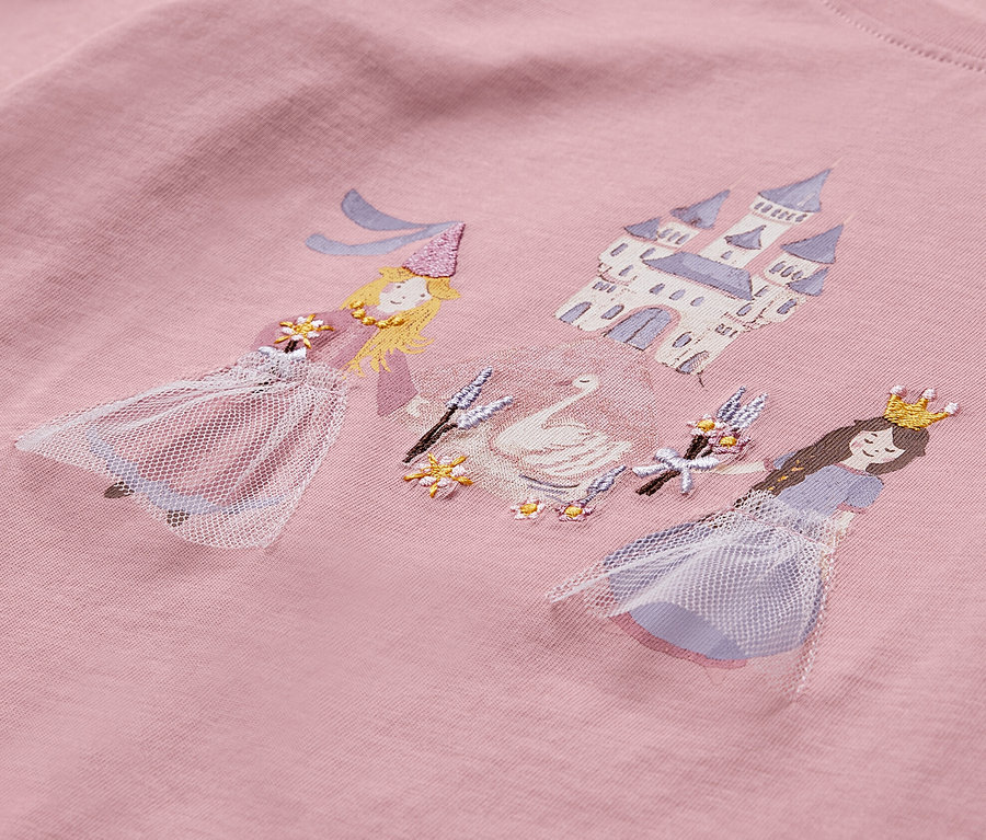 Gros plan sur un t-shirt à manches longues rose orné de deux princesses, d'un cygne et d'un château.